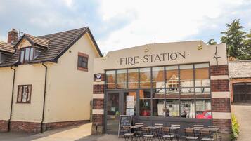 A building labeled "Fire Station" with a large window, outdoor seating area, and a brick facade.