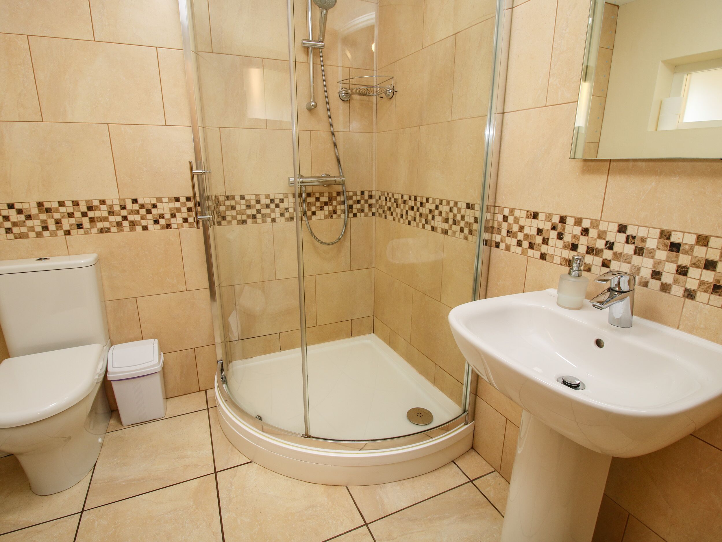 A bathroom with a glass-enclosed shower, a white sink, and a toilet.