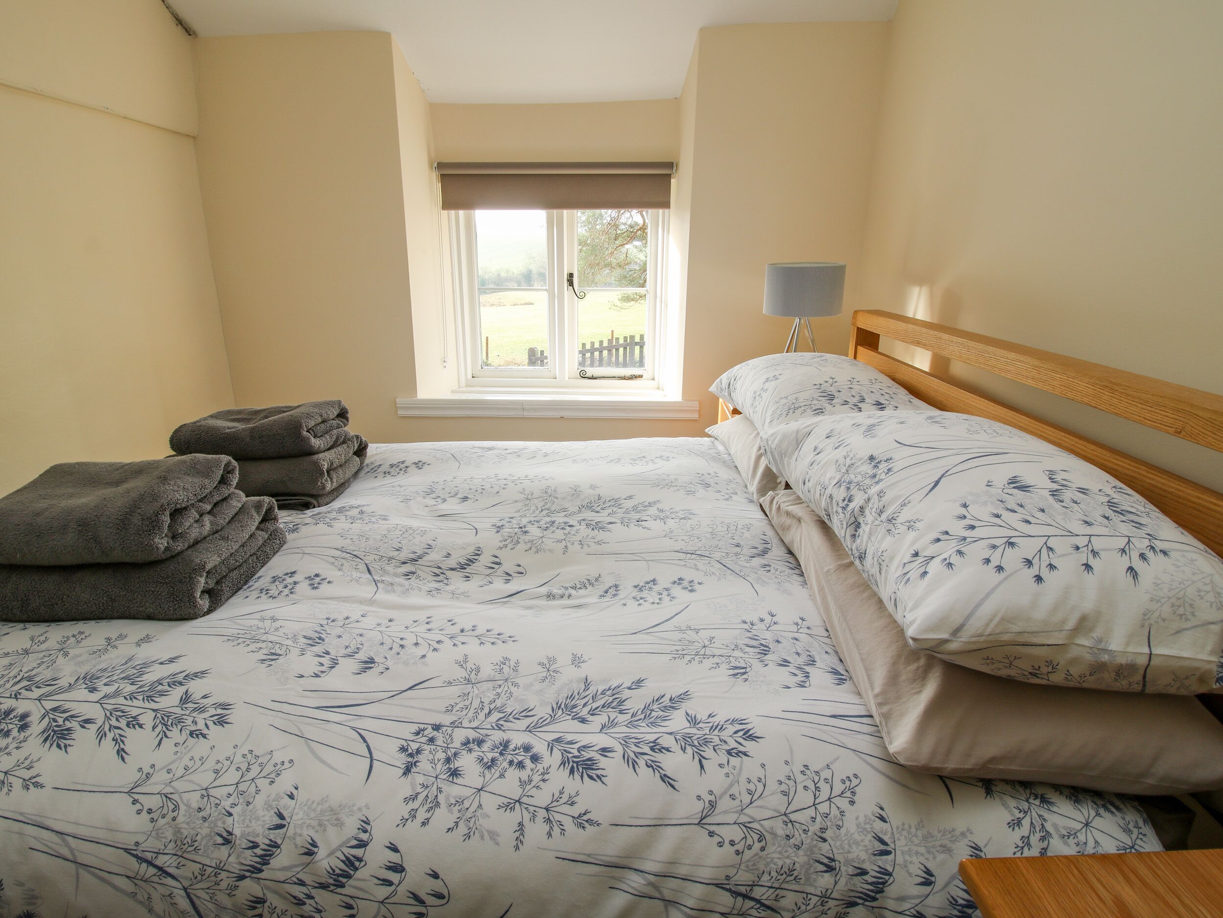 A bedroom with a bed, a window with a view, and a lamp.