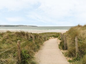 Un sendero de madera que lleva a una playa, con una valla a cada lado.