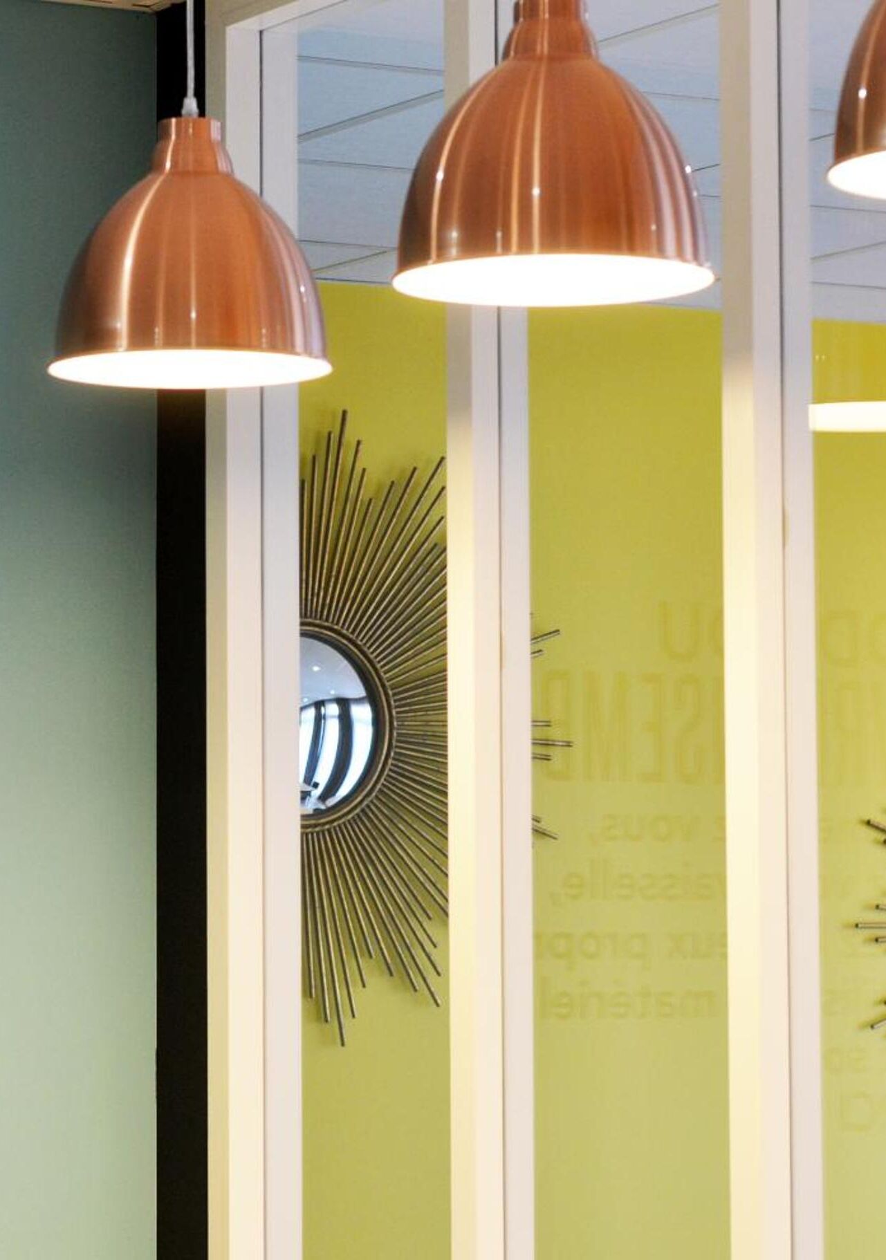 A wall with a sunburst mirror and a green wall with text.