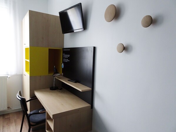 A compact workspace with a desk, chair, and a mounted TV.
