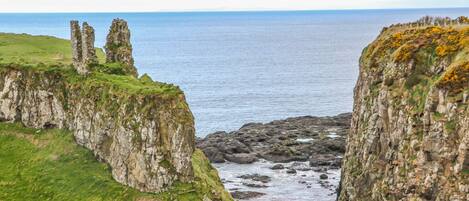 A coastal landscape with rocky cliffs and a view of the sea.