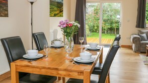 A dining area with a wooden table set for four, black chairs, a vase with flowers, and a painting on the wall. - Croft Cottage (Lancaster)
