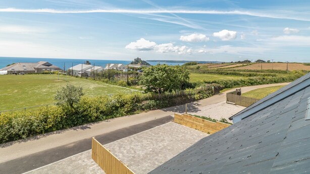 A residential area with a view of the sea, houses, and a castle in the distance. - Sea Dreams (Marazion)