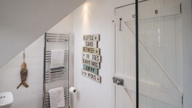 Een badkamer met een handdoekhouder, toilet en douche.