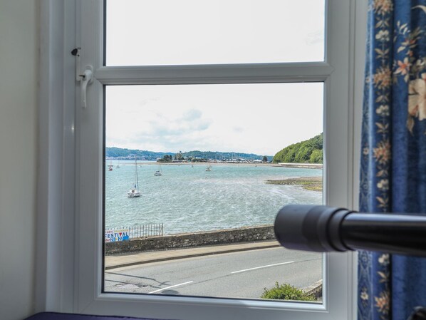Una ventana con vista a un puerto, barcos y un paisaje costero.