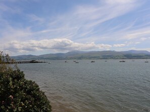 Un lago tranquilo con barcos, un muelle y montañas al fondo.