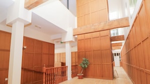 A spacious interior with high ceilings, wooden paneling, and a central staircase. - Wye Apartment, Litton Mill (Buxton)
