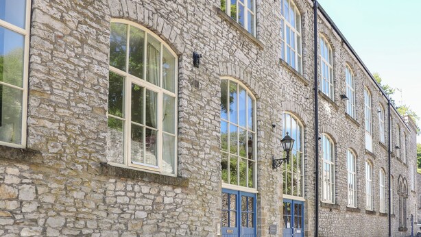 A stone building with large windows and blue doors. - Wye Apartment, Litton Mill (Buxton)