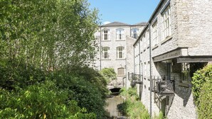 A stone building with a narrow passageway and a bridge. - Wye Apartment, Litton Mill (Buxton)