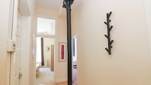 A hallway with wooden flooring, a black wall-mounted light fixture, and a door on the left. - Wye Apartment, Litton Mill (Buxton)