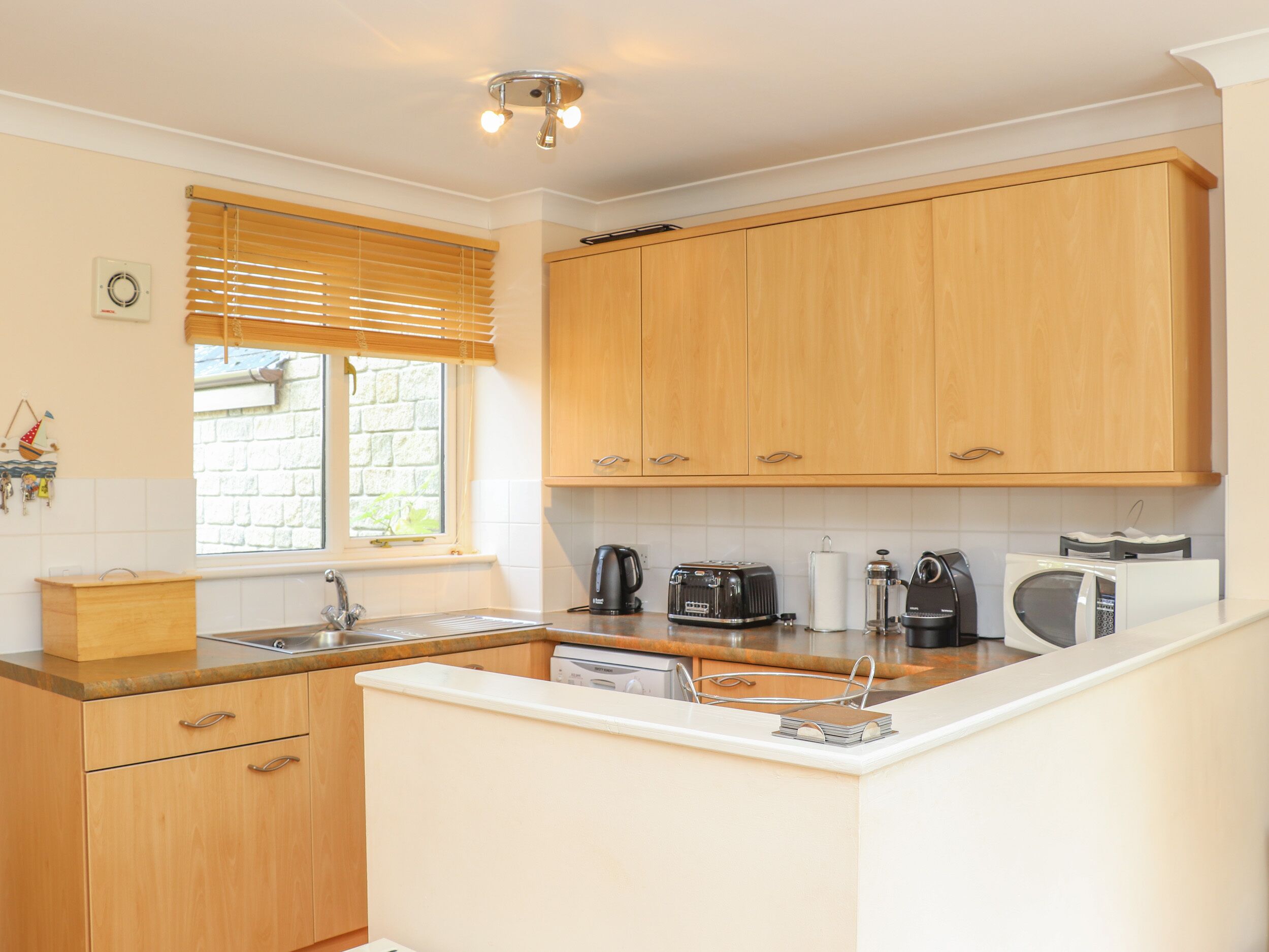 A kitchen with wooden cabinets, a built-in sink, and a window with blinds.