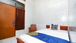 A hotel room with a bed, wooden headboard, a chair, and a window with curtains. - SPOT ON 2011 Hotel Mekar Sari (Surakarta)