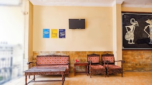 A room with a sofa, chairs, a TV, and a wall with a painting. - SPOT ON 2011 Hotel Mekar Sari (Surakarta)