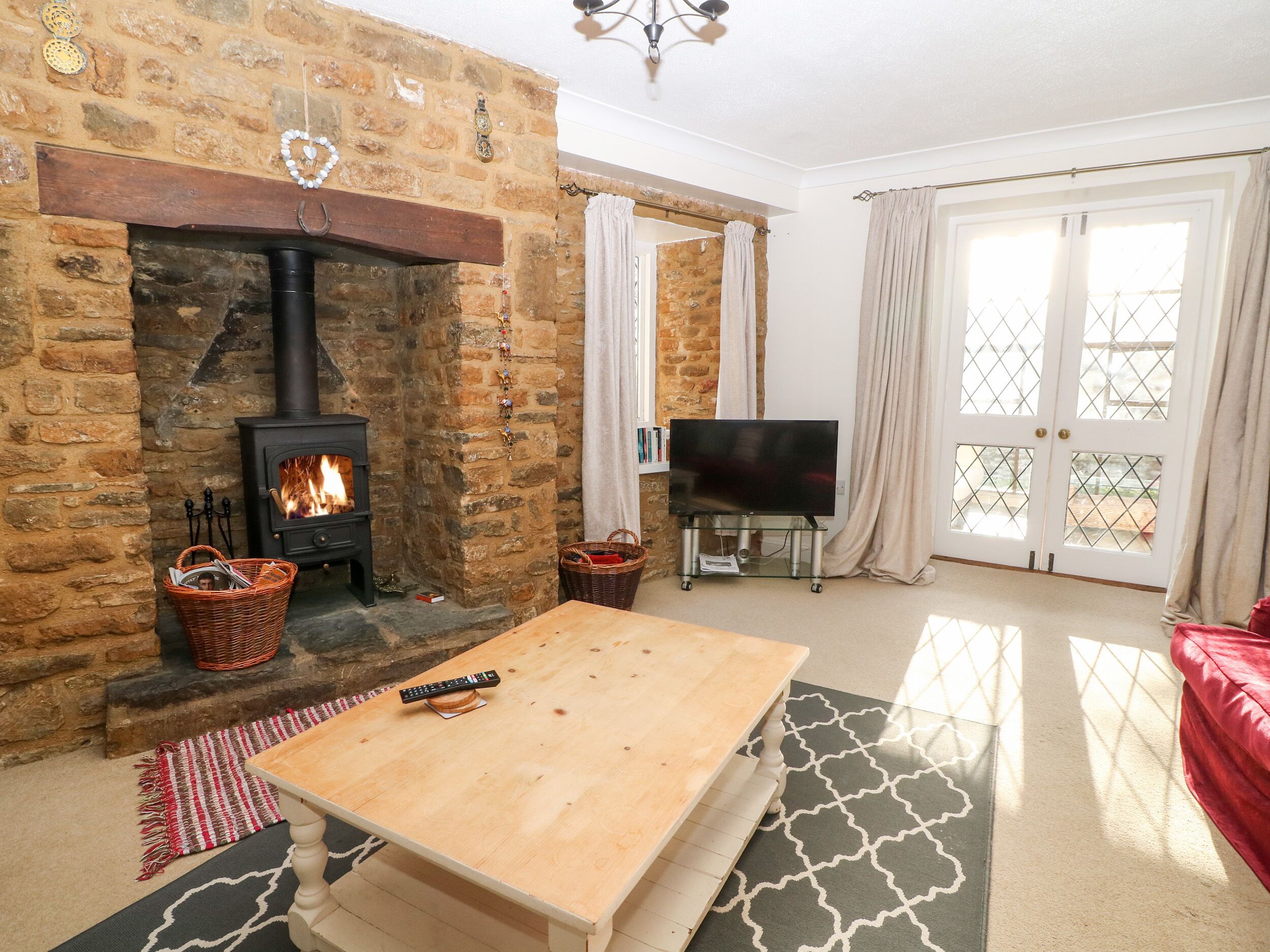 A cozy living room with a stone fireplace, a television, and a red sofa.
