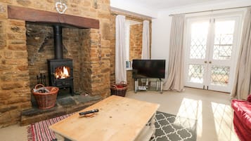 A cozy living room with a stone fireplace, a television, and a red sofa.