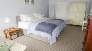 Une chambre à coucher comprenant un lit, une table de chevet, une lampe, une armoire et une petite table sur laquelle est posé un objet décoratif.
