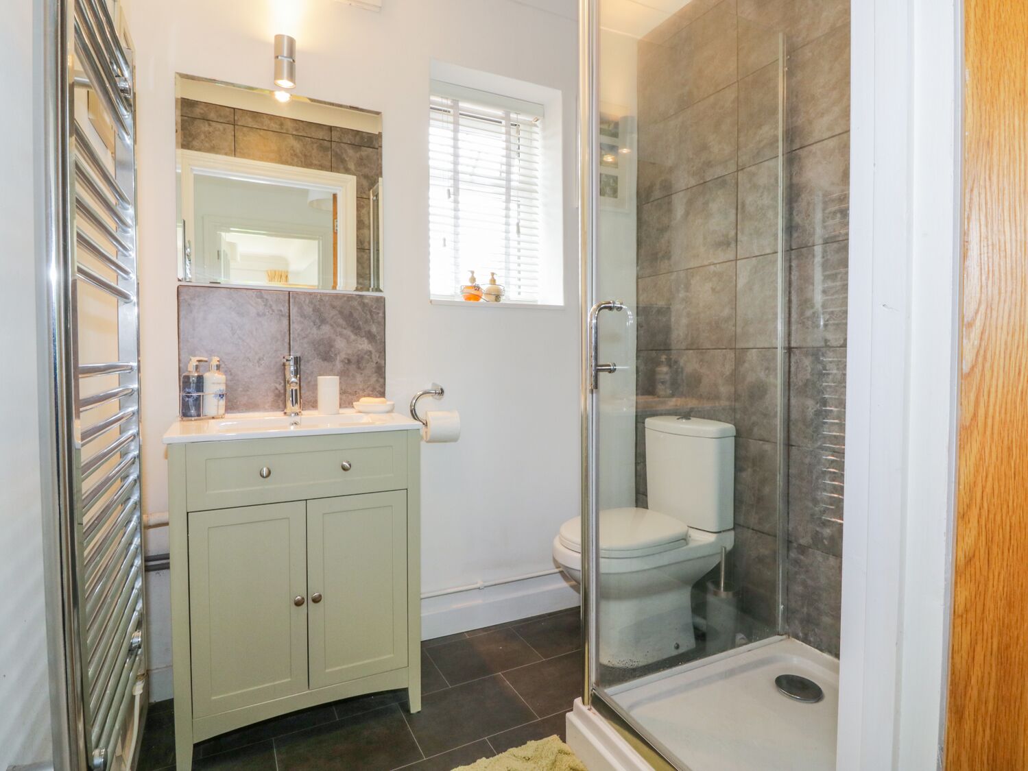 Un bagno moderno con doccia vetrata, un water bianco e un mobile lavabo con specchio e lavandino.