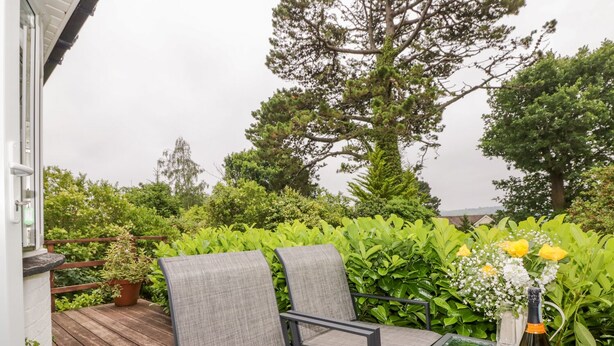 A balcony with a glass table, two grey chairs, and a plate of strawberries and croissants. - Hilltop (Totnes)