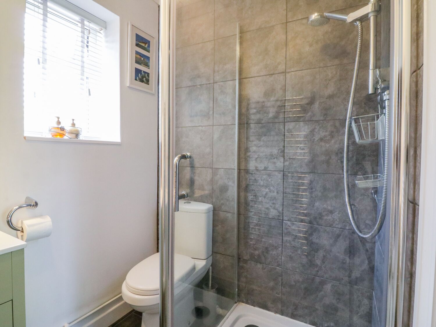 A modern bathroom with a glass-enclosed shower, a toilet, and a sink.