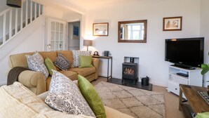 A cozy living room with a sofa, a television, a fireplace, and a staircase. - Hilltop (Totnes)