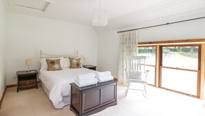 A bedroom with a large bed, two bedside tables, a chair, and a view of the outdoors. - Cardean Mill (Blairgowrie)