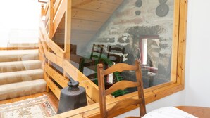 A rustic attic bedroom with a wooden staircase, a large window, and a stone wall. - Cardean Mill (Blairgowrie)