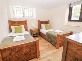 Una habitación con dos camas de madera, una mesita de noche con una lámpara y una ventana con diseño de celosía.