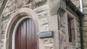 A stone building with a wooden door and a sign reading "ANDLESTONE". - Andlestone (Matlock)