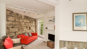 Una sala de estar con pared de piedra, un sofá rojo, un sofá negro y una chimenea.