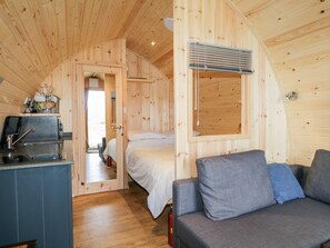 A cozy cabin interior with a kitchenette, a bed, and a seating area.