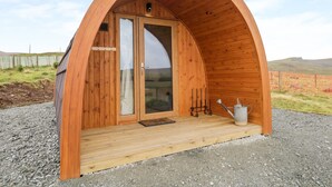Une structure arquée en bois, dotée d’une porte et d’un petit espace formant un porche.