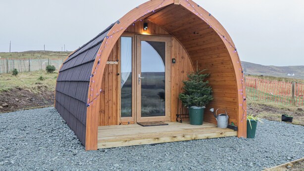 Une petite structure en bois, dotée d’une arche, d’une porte et d’un petit espace porche.