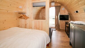 Un intérieur en bois comprenant un lit, un téléviseur et une petite kitchenette.