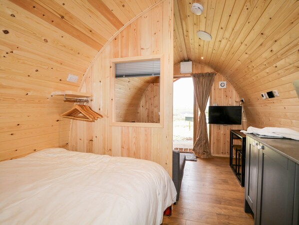 A wooden interior with a bed, a TV, and a small kitchenette. - Garraidh Ghorm Pod (Kilmuir)