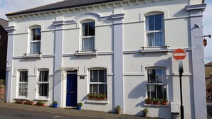A white two-story building with a blue door and multiple windows. - Lancaster House (Sandown)