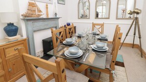A dining room with a glass table, wooden chairs, and a blue vase on a wooden cabinet. - Lancaster House (Sandown)