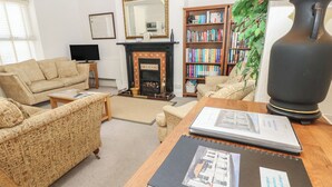 A living room with a fireplace, a bookshelf, and a table with a book. - Lancaster House (Sandown)