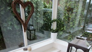 A room with a window, a heart-shaped decoration, a small shelf with a plant, a candle holder, and a drying rack. - Quayside (Whitby)