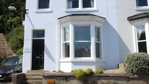 A two-story building with a bay window, a door, and a small garden area. - Quayside (Whitby)