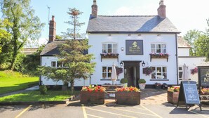A traditional pub named "Hare & Hounds" with a white facade, black roof, and flower boxes on the windows. - The Stables (Frodsham)