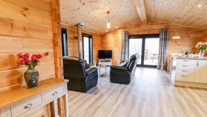 A cozy cabin interior with a wooden interior, a sofa, a TV, and a dining area. - Bryn Eiddon Log Cabin (Machynlleth)