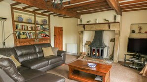 A cozy living room with a leather sofa, a coffee table, a fireplace, a bookshelf, and a television. - Dale View (Skipton)