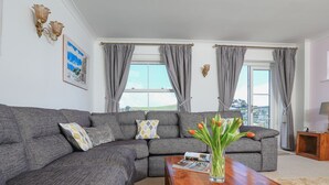 Ein modernes Wohnzimmer mit einem grauen Ecksofa, einem Holztisch und einer Vase mit Tulpen.