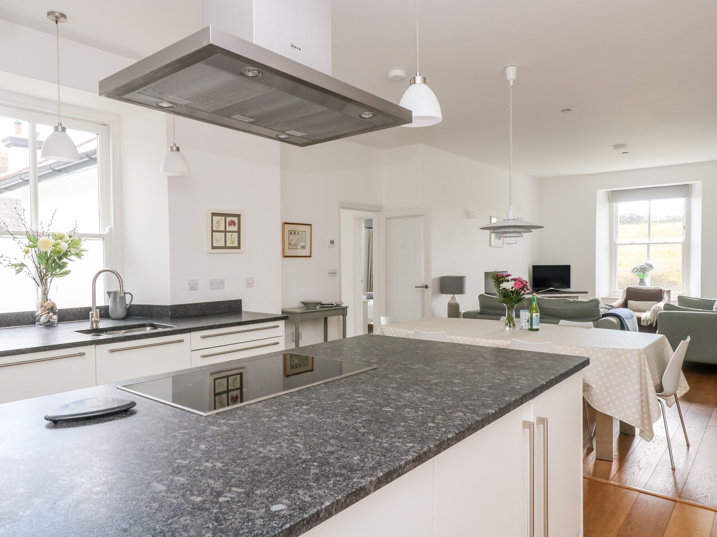A modern kitchen with a large island, white cabinetry, and pendant lighting.