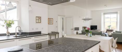 A modern kitchen with a large island, white cabinetry, and pendant lighting.