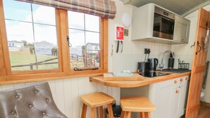 Eine gemütliche Küche mit Holzstühlen, einem gepolsterten Sessel und Blick ins Freie.