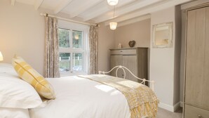 Ein Schlafzimmer mit Bett, Kleiderschrank und einem Fenster mit Vorhängen.