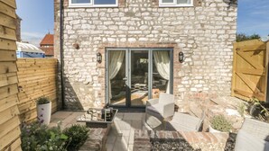 A stone house with a wooden deck, a sliding glass door, and a satellite dish. - Chalkstone Cottage (Bridlington)